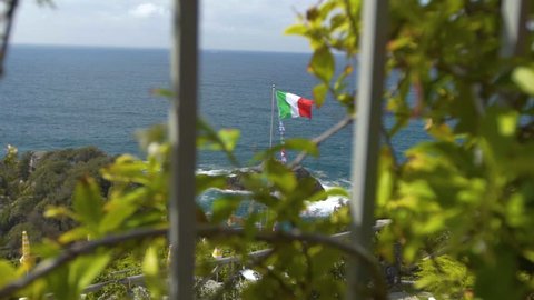 Italian flag waving in slow motion against the ocean in cinque terre, spezia, Italy
