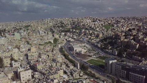 Beautiful aerial clip overcast day of gray skies over Amman Jordan showing the city's multi-tiered architecture and landscape - taken by a drone