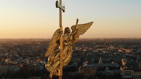 Aerial flying around an angel on spire of Peter and Paul Fortress at sunset, close-up. Historical panorama of St. Petersburg