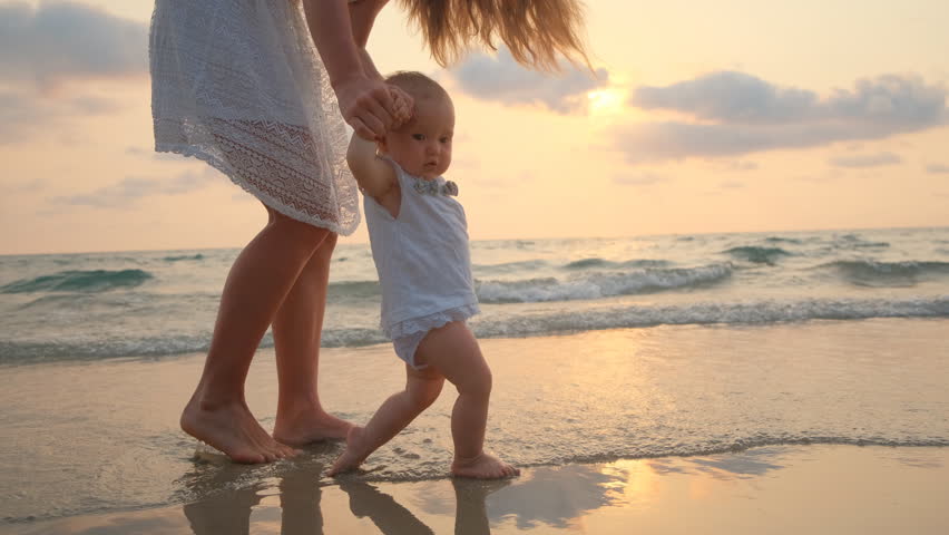 Young Beautiful Woman Walks With Her Little baby On The Seashore At Sunsetg Beautiful Woman Walks With Her Little baby On The Seashore At Sunset. 4k | Shutterstock HD Video #1028707469