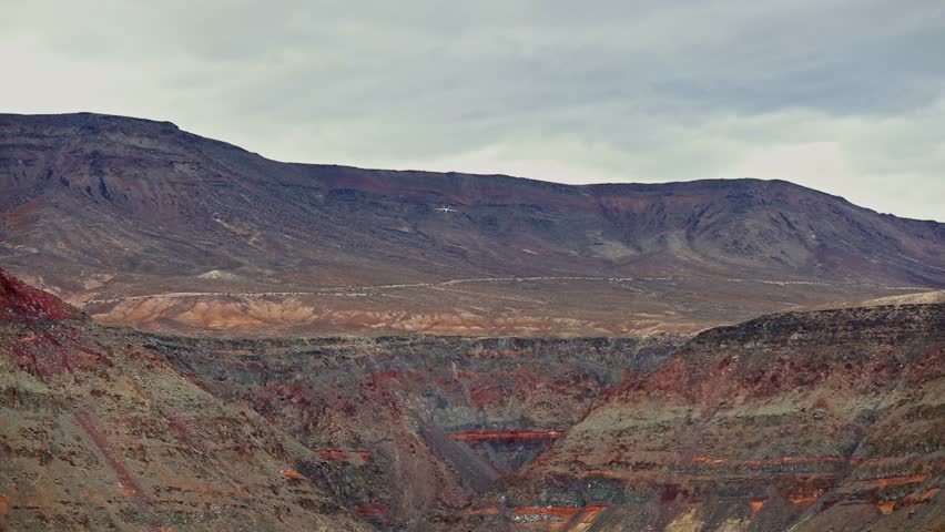 Slow motion, close-up view of a fighter jet flying through a colorful canyon, slow roll from left to right