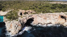 a drone shot panning around a large sea arch near cala varques in majorca