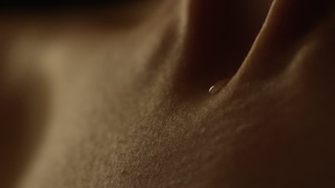 A drop of water flows through the woman body in a macro shot.
