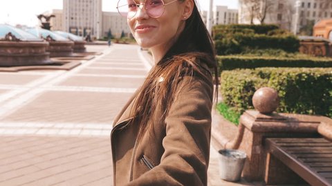 Back view.Follow me romantic concept. Young woman with long hair holding her boyfriend's hand. Smiling girl running in the city. Turning around in sunglasses. Having fun and going crazy. Slow motion