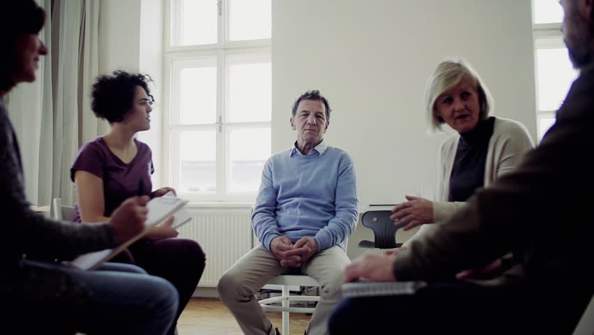 Men and women sitting in a circle during group therapy, talking. | Shutterstock HD Video #1028731445