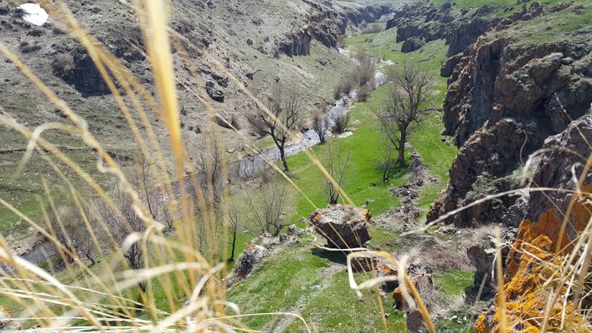 in a deep gorge offers beautiful views of nature and the river flowing between the high mountains, in the vicinity of dry grass swaying in the wind