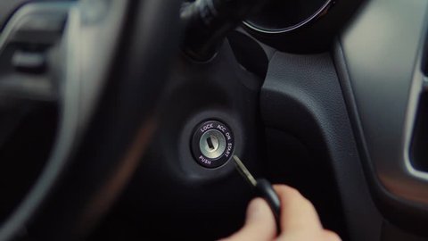 Close-up shot of a man putting his car keys into socket and starting the engine. Man's hand with car keys. Igniting car.