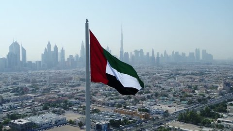 Aerial view of Dubai flag and in background Dubai skyline