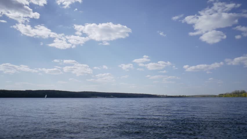 Beautiful lake with wind and blue sky background, people playing water sport like windsurf and relax on summer holiday