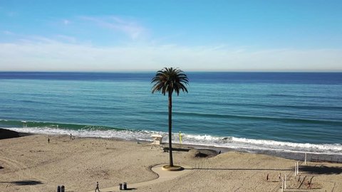 Aerial drone video over Moonlight Beach on sunny summer morning, overlooking the blue ocean and sky, in Encinitas California.