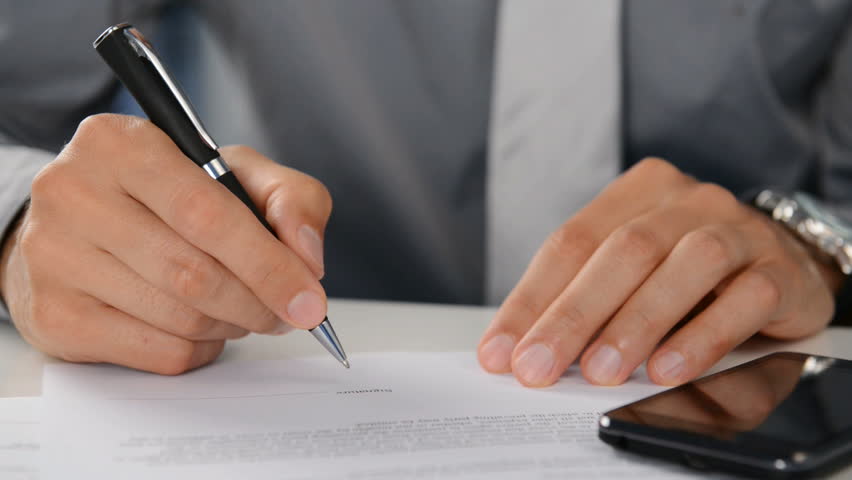 Close Up Of A Businessman Signing Contract. The male hand signing a business deal in a office. Close up of a signature for a business report. Business worker signing the contract. Royalty-Free Stock Footage #10287638