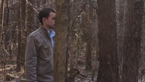 Ungraded: Bearded man walks wildly through the forest with bushes and thickets, looking around with caution. Ungraded H.264 from camera without re-encoding.