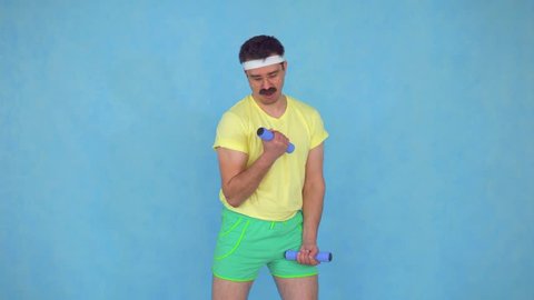 Funny young man trainer with a mustache from 80's is engaged with dumbbells