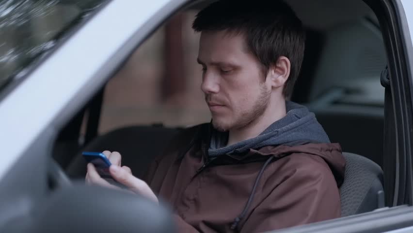 Close up shoot. Young man driver use smartphone, sitting in the car. Slowmotion.  | Shutterstock HD Video #1028773535