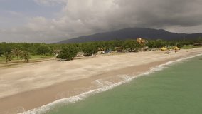 Aerial drone footage above Langkawi beach, Malaysia - Landscape scene of beach, waves and people
