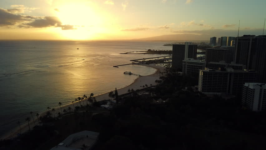 Waikiki motion time lapse. The sun sets on Honolulu, Hawaii. Another day has passed, boats head to dock, and city lights brighten.