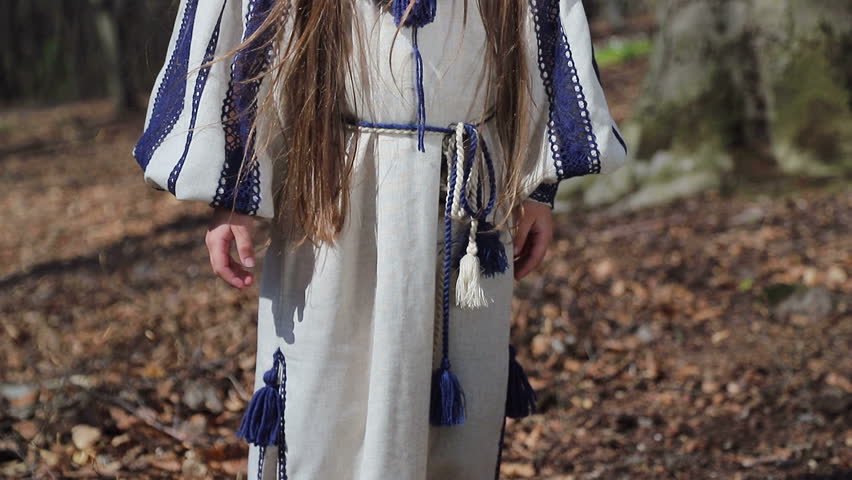 A little girl in the woods picks up a whisk of white forest flowers, and puts it on his head