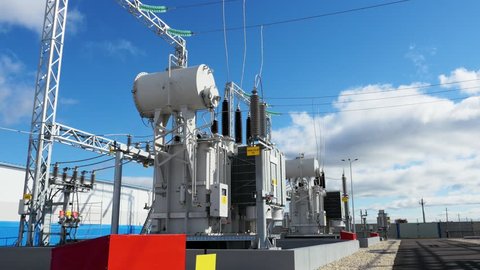 modern electric substation with power lines and transformers against blue sky with clouds on spring day