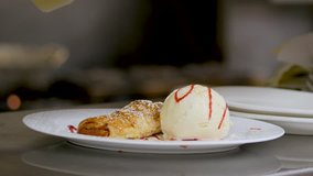 Close Up Shot Of An Ice Cream And Strudel Dessert On The White Plate. The panning close up video of ice cream roll together with strudel on the plate.