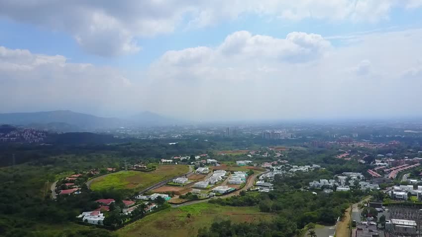 AERIAL: extremely slow movement over the mixture of suburban and mountainous terrain found in Cali, Colombia on a very overcast day.