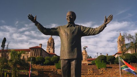 Pretoria, South Africa - circa 2019: Dynamic, cinematic wrapping movement of Nelson Mandela statue, below Union Buildings. Statue against buildings, then isolated against sky. Outstretched hands