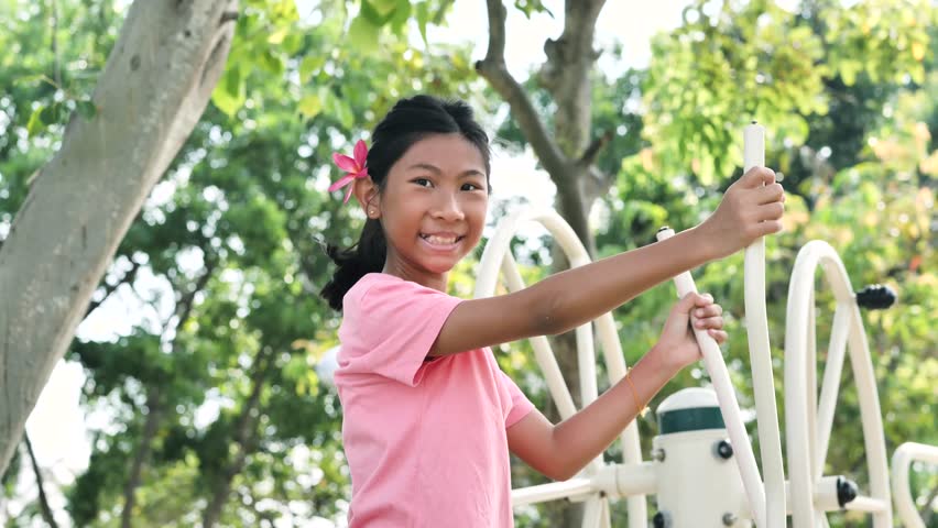 Happy Asian girl using exercise equipment in the park outdoor, slow 