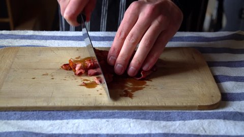Front View of a Man Chef chopping crispy bacon for breakfast. Food Preparation.
