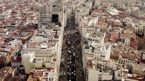 Long aerial shot of the city center Madrid. The Gran via on a busy day with citylife on the streets. People and cars are roaming around in the capital of Spain.