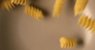 Fusilli Italian pasta falling and rotating in slow motion. Extreme close up top view, shot on RED 6K camera