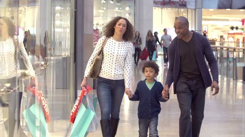 Family walking through shopping mall carrying sale bags looking at window displays.Shot on Sony FS700 at frame rate of 100fps