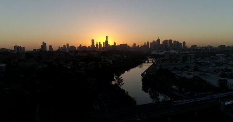 Aerial shot along yarra river in expensive suburb in melbourne, Australia, with the silhouette city on the horizon, drone.