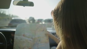 Couple pointing at map in car. Cropped shot of smiling young woman holding map and showing route to male driver. Transportation concept