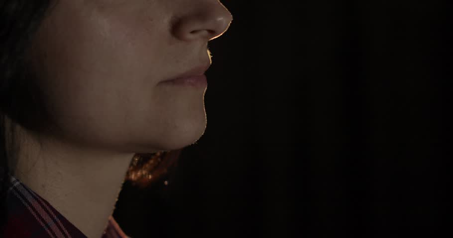 Beautiful, young woman smoking hookah. Attractive girl smoking flavored tobacco. Blow out smoke close-up on black background