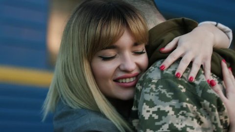 Romantic reunion. Close up view of beautiful young woman feeling happy while hugging embracing her soldier boyfriend. Turning back home, homecoming, welcomed by wife. happiness
