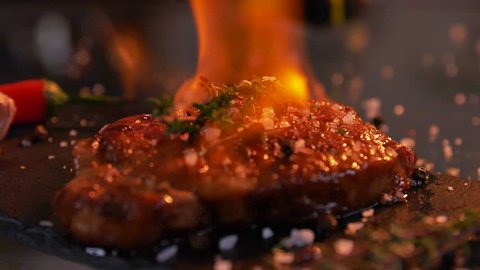 Close-up view of juicy cooked slice of meat and fresh vegetables with flames. bbq burn original recipe of dish. Professional cooking, exotic meal cook recipe, preparing food. Slow motion