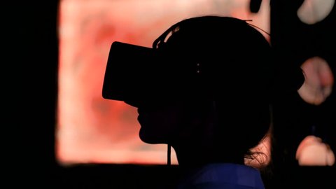 Woman using virtual reality headset and looking around at interactive technology exhibition. VR, augmented reality, digital art, futuristic, interactive, immersive and entertainment concept