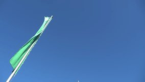 Narrow vertical flag waving in the wind against the blue sky. Sport footage 4k
