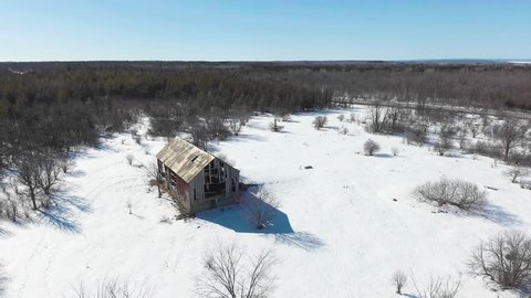 Drone footage circling old barn in the winter.