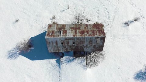 Top-down drone footage over rusty roof of old barn in the winter.