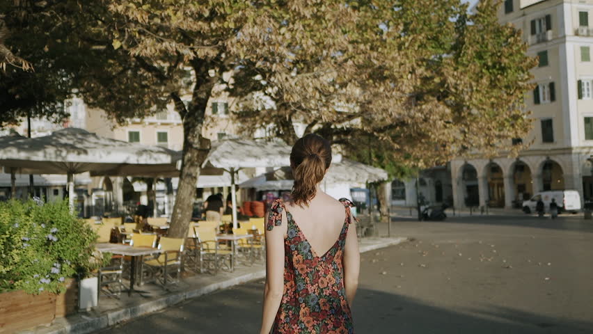 Beautiful blonde girl walking in narrow street in central Kerkyra, Greece on a sunny day