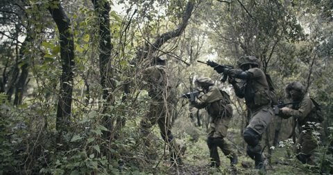 Squad of fully armed commando soldiers during combat in a forest scenery