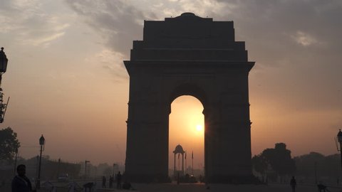 DELHI, INDIA - MARCH 14, 2019:  a multi axis gimbal steadicam clip walking towards india gate at sunrise with the sun framed by the arch in new delhi, india