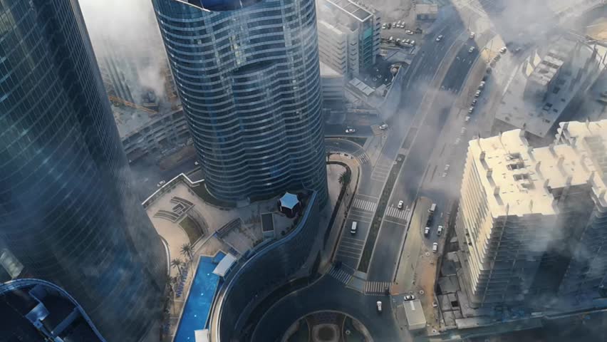 Top aerial view shot of skyscrapers in the city with fog clouds passing by - Abu Dhabi Al Reem island Sun and Sky towers