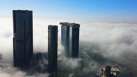 Top aerial view shot of skyscrapers in the city with fog clouds passing by - Abu Dhabi Al Reem island Sun and Sky towers