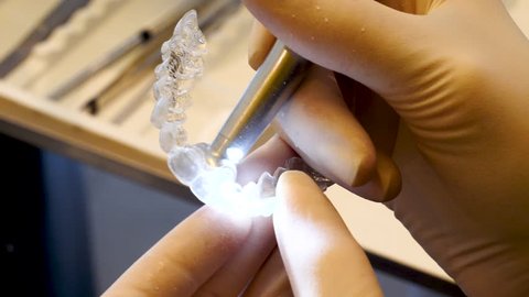 Tight close up of a dentist checking an invisalign retainer