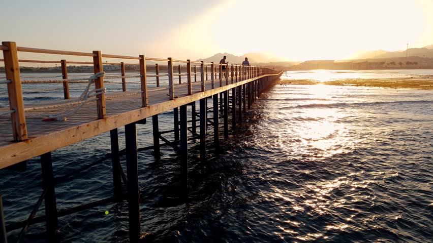 4k video of beautiful long wooden pier in the sea at sunset light