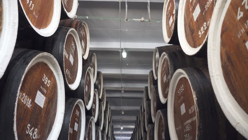 Barrels of cognac, wine or whiskey. Extract of brandy in oak barrels. Alcohol warehouse. Hundreds of barrels in an underground vault. Camera movement between barrels.