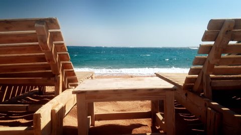 4k footage of two old wooden lounges on sea beach at windy day