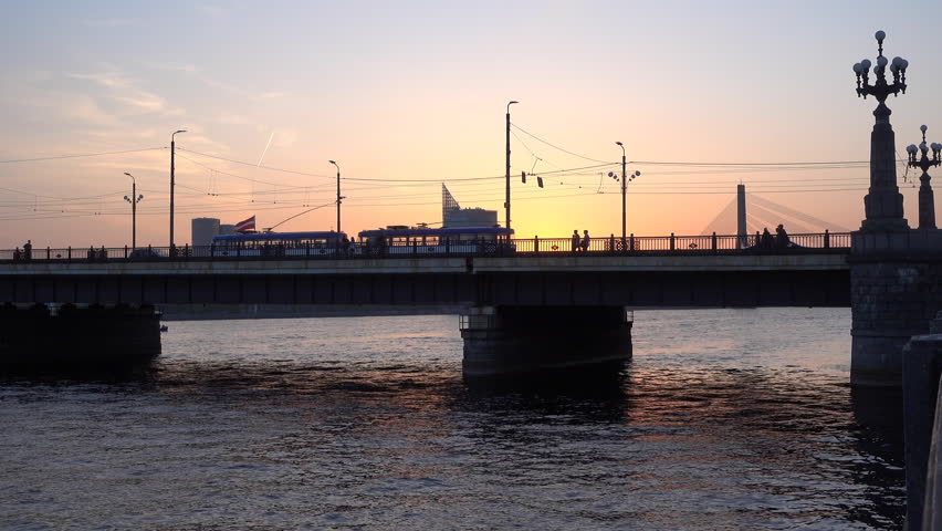 Sunset with the silhouette of the Stone Bridge in Riga, Latvia. A tram passes.
