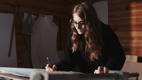 Inspired female architect drawing an architectural plan on the big table indoors. Arkistovideo